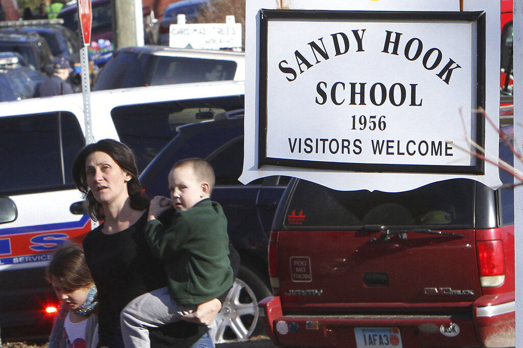 A parent walks away from the Sandy Hook Elementary School with her children following the 2012 shooting at the school in Newtown, Conn. The families of nine victims of the Sandy Hook school shooting have agreed to a $73 million settlement of a lawsuit against the maker of the rifle used to kill 20 first graders and six educators     PHOTO CREDIT: Frank Becerra Jr.