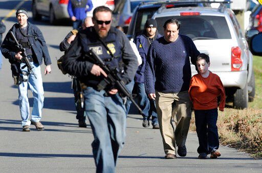 FILe — Parents leave a staging area after being reunited with their children following a shooting at the Sandy Hook Elementary School in Newtown, Conn., Friday, Dec. 14, 2012. The families of nine victims of the Sandy Hook Elementary School shooting have agreed to a settlement of a lawsuit against the maker of the rifle used to kill 20 first graders and six educators in 2012, according to a court filing, Tuesday, Feb. 15, 2022. (AP Photo/Jessica Hill, File)    PHOTO CREDIT: Jessica Hill