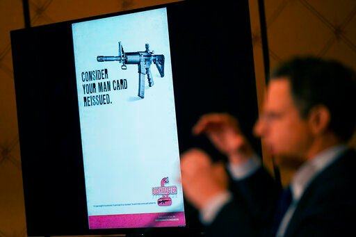 An image of the advertising used for an AR-15-style rifle is displayed while attorney Josh Koskoff speaks during a news conference in Trumbull, Conn., Tuesday, Feb. 15, 2022. The families of nine victims of the Sandy Hook Elementary School shooting have agreed to a $73 million settlement of a lawsuit against the maker of the rifle used to kill 20 first graders and six educators in 2012, their attorney said Tuesday. (AP Photo/Seth Wenig)    PHOTO CREDIT: Seth Wenig