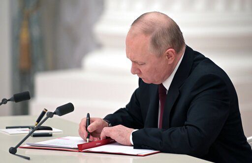 Russian President Vladimir Putin signs a document recognizing the independence of separatist regions in eastern Ukraine in the Kremlin in Moscow, Russia, Monday, Feb. 21, 2022. Russia