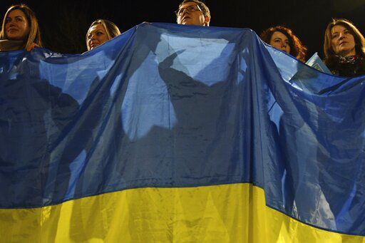 People wave a huge Ukrainian national flag during an action in support of country in Kramatorsk, Ukraine, Wednesday, Feb. 23, 2022. U.S. President Joe Biden announced the U.S. was ordering heavy financial sanctions against Russia, declaring that Moscow had flagrantly violated international law in what he called the "beginning of a Russian invasion of Ukraine." (AP Photo/Andriy Andriyenko)    PHOTO CREDIT: Andriy Andriyenko