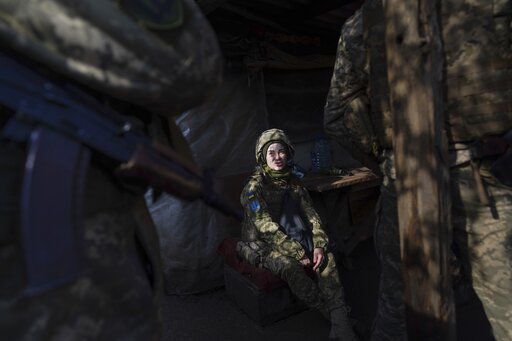 A Ukrainian soldier talks with her comrades sitting in a shelter at the line of separation between Ukraine-held territory and rebel-held territory near Svitlodarsk, eastern Ukraine, Wednesday, Feb. 23, 2022. U.S. President Joe Biden announced the U.S. was ordering heavy financial sanctions against Russia, declaring that Moscow had flagrantly violated international law in what he called the "beginning of a Russian invasion of Ukraine." (AP Photo/Evgeniy Maloletka)    PHOTO CREDIT: Evgeniy Maloletka