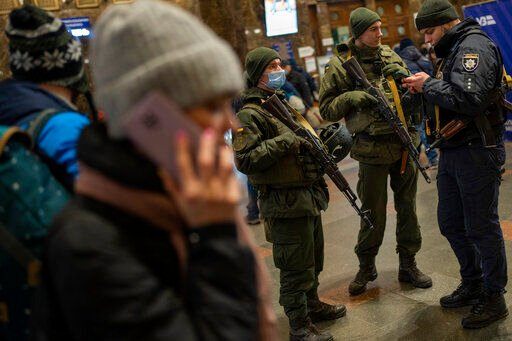 Ukrainian soldiers stand guard as people try to leave at the Kyiv train station, Ukraine, Thursday, Feb. 24, 2022. Russian troops have launched their anticipated attack on Ukraine. Big explosions were heard before dawn in Kyiv, Kharkiv and Odesa as world leaders decried the start of an Russian invasion that could cause massive casualties and topple Ukraine