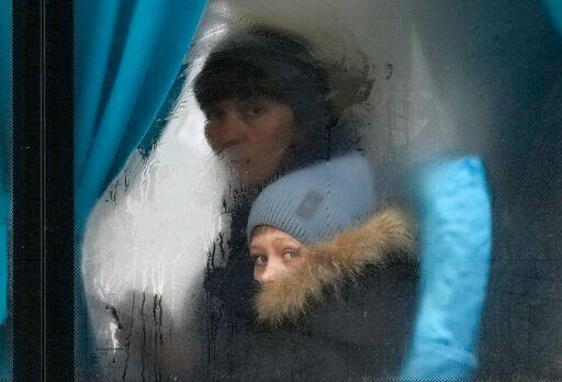A woman and child peer out of the window of a bus as they leave Sievierodonetsk, the Luhansk region, eastern Ukraine, Thursday, Feb. 24, 2022. Russian President Vladimir Putin on Thursday announced a military operation in Ukraine and warned other countries that any attempt to interfere with the Russian action would lead to "consequences you have never seen." (AP Photo/Vadim Ghirda)    PHOTO CREDIT: Vadim Ghirda