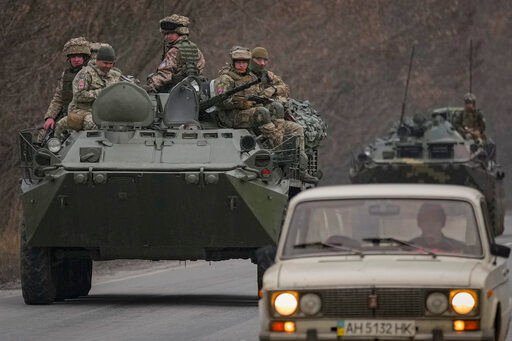 Ukrainian servicemen sit atop armored personnel carriers driving on a road in the Donetsk region, eastern Ukraine, Thursday, Feb. 24, 2022. Russian President Vladimir Putin on Thursday announced a military operation in Ukraine and warned other countries that any attempt to interfere with the Russian action would lead to "consequences you have never seen." (AP Photo/Vadim Ghirda)    PHOTO CREDIT: Vadim Ghirda