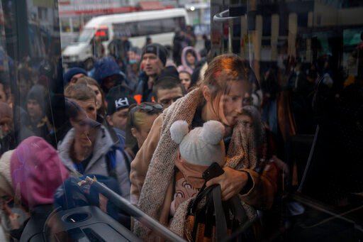 A woman holds her baby as she gets on a bus leaving Kyiv, Ukraine, Thursday, Feb. 24, 2022. Russia launched a wide-ranging attack on Ukraine on Thursday, hitting cities and bases with airstrikes or shelling, as civilians piled into trains and cars to flee. (AP Photo/Emilio Morenatti)    PHOTO CREDIT: Emilio Morenatti