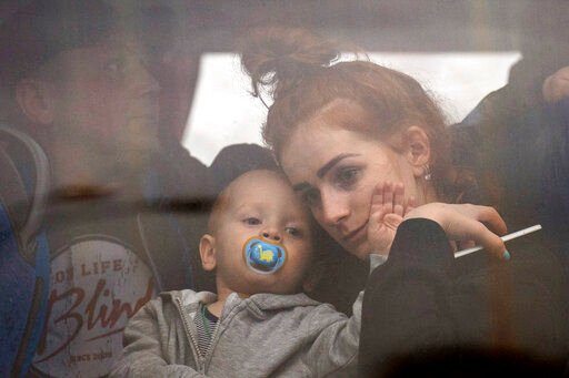 A woman holds her baby inside a bus as they leave Kyiv, Ukraine, Thursday, Feb. 24, 2022. Russia launched a wide-ranging attack on Ukraine on Thursday, hitting cities and bases with airstrikes or shelling, as civilians piled into trains and cars to flee. (AP Photo/Emilio Morenatti)    PHOTO CREDIT: Emilio Morenatti