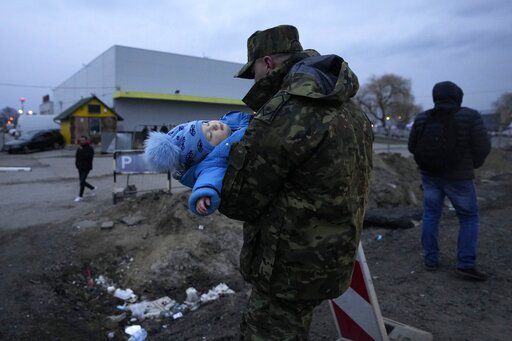 A Polish soldier carries a baby of a Ukrainian refugee upon their arrival at the border crossing in Medyka, southeastern Poland, Wednesday, March 2, 2022. Seven days into the war, roughly 874,000 people have fled Ukraine and the U.N. refugee agency warned the number could cross the 1 million mark soon. (AP Photo/Markus Schreiber)    PHOTO CREDIT: Markus Schreiber