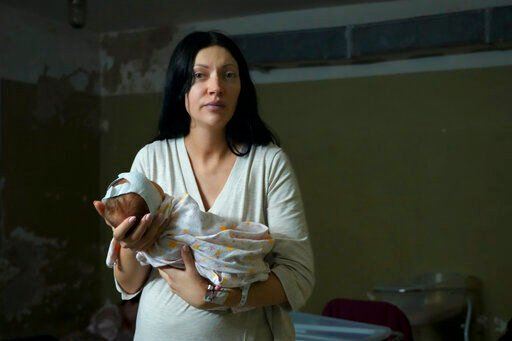 A woman, who did not want to be identified, poses for a photograph as she holds her newborn girl in the basement of a maternity hospital converted into a medical ward and used as a bomb shelter during air raid alerts, in Kyiv, Ukraine, Wednesday, March 2, 2022. Russian forces have escalated their attacks on crowded cities in what Ukraine