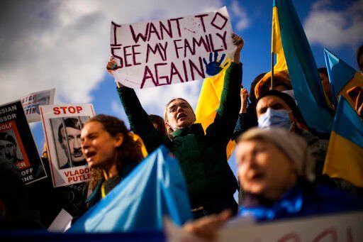 Pro-Ukrainian people hold up placards and wave Ukrainian flags as they shout slogans during a protest against Russia