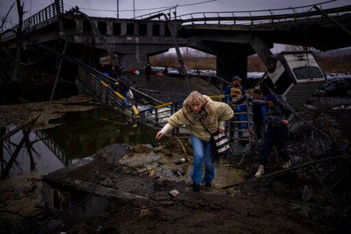 A woman runs as she flees with her family across a destroyed bridge in the outskirts of Kyiv, Ukraine, Wednesday, March 2. 2022. Russia renewed its assault Wednesday on Ukraine’s second-largest city in a pounding that lit up the skyline with balls of fire over populated areas, even as both sides said they were ready to resume talks aimed at stopping the new devastating war in Europe. (AP Photo/Emilio Morenatti)    PHOTO CREDIT: Emilio Morenatti