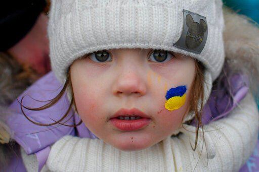 Zlata, 3 and half year-old, fleeing the conflict from neighbouring Ukraine with her face painted in the colours of the Ukrainian flag stands at the Romanian-Ukrainian border, in Siret, Romania, Thursday, March 3, 2022. The number of people sent fleeing Ukraine by Russia
