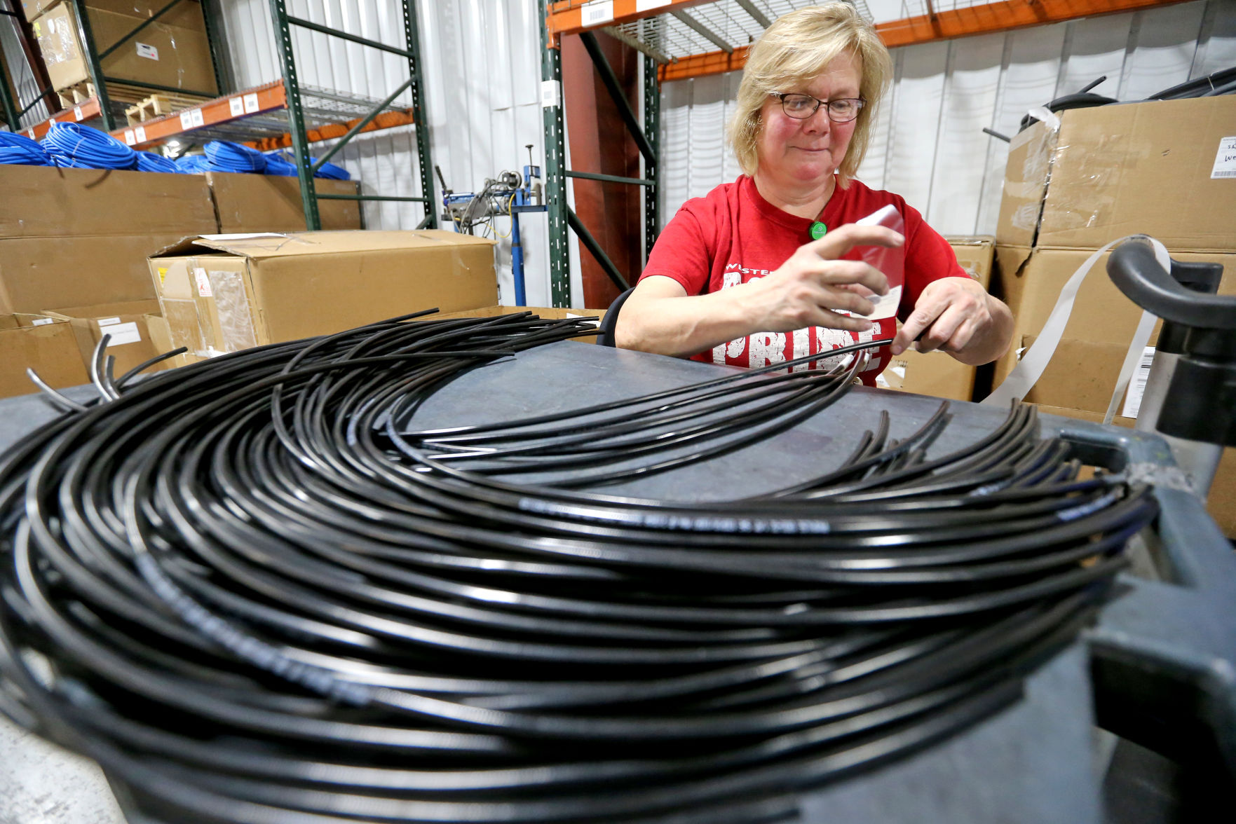 Linda Besler applies a label on a hydraulic hose at ProPulse, a Schieffer company, in Peosta, Iowa, on Friday.    PHOTO CREDIT: JESSICA REILLY, Telegraph Herald