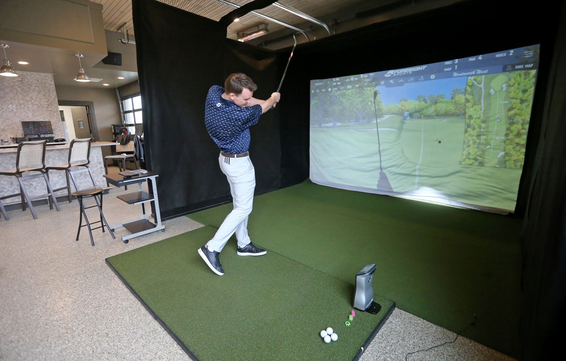 Carson Hillery, recreation supervisor at Thunder Hills Country Club, uses the golf simulator in the newly renovated cabana at the club in Peosta, Iowa, on Thursday, March 3, 2022.    PHOTO CREDIT: JESSICA REILLY