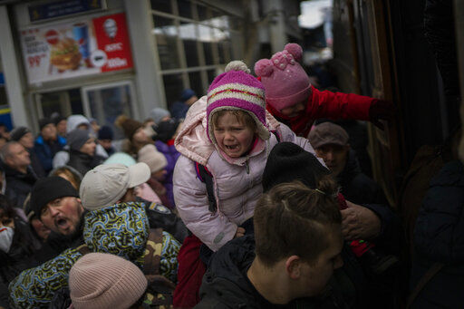 People holding their children struggle to get on a train to Lviv at the Kyiv station, Ukraine, Monday, March 7, 2022. Russia announced yet another cease-fire and a handful of humanitarian corridors to allow civilians to flee Ukraine. Previous such measures have fallen apart and Moscow