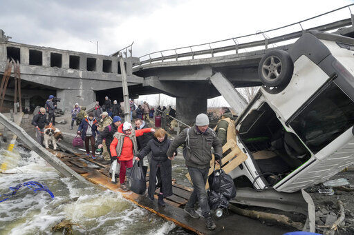 People cross an improvised path under a destroyed bridge while fleeing the town of Irpin close to Kyiv, Ukraine, Monday, March 7, 2022.Russia announced yet another cease-fire and a handful of humanitarian corridors to allow civilians to flee Ukraine. Previous such measures have fallen apart and Moscow’s armed forces continued to pummel some Ukrainian cities with rockets Monday. (AP Photo/Efrem Lukatsky)    PHOTO CREDIT: Efrem Lukatsky