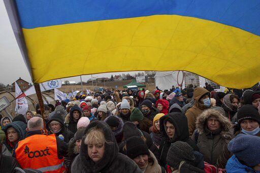 A Ukrainian volunteer Oleksandr Osetynskyi, 44 holds a Ukrainian flag and directs hundreds of refugees after fleeing from the Ukraine and arriving at the border crossing in Medyka, Poland, Monday, March 7, 2022. Russia announced yet another cease-fire and a handful of humanitarian corridors to allow civilians to flee Ukraine. Previous such measures have fallen apart and Moscow’s armed forces continued to pummel some Ukrainian cities with rockets Monday. (AP Photo/Visar Kryeziu)    PHOTO CREDIT: Visar Kryeziu