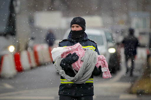 A firefighter holds the baby of a refugee fleeing the conflict from neighbouring Ukraine at the Romanian-Ukrainian border, in Siret, Romania, Monday, March 7, 2022. (AP Photo/Andreea Alexandru)    PHOTO CREDIT: Andreea Alexandru