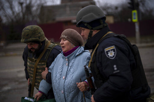 Ukrainian police officers help a woman fleeing as the artillery echoes nearby in Irpin, in the outskirts of Kyiv, Ukraine, Monday, March 7, 2022. (AP Photo/Emilio Morenatti)    PHOTO CREDIT: Emilio Morenatti