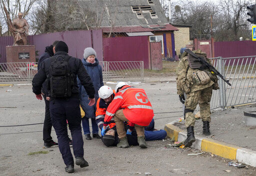 Paramedics administer first aid to an elderly man who fainted after crossing the Irpin river to flee the town of Irpin, close to Kyiv, Ukraine, Monday, March 7, 2022. Irpin residents continue to leave the ruined city under Russian heavy artillery shelling. (AP Photo/Efrem Lukatsky)    PHOTO CREDIT: Efrem Lukatsky