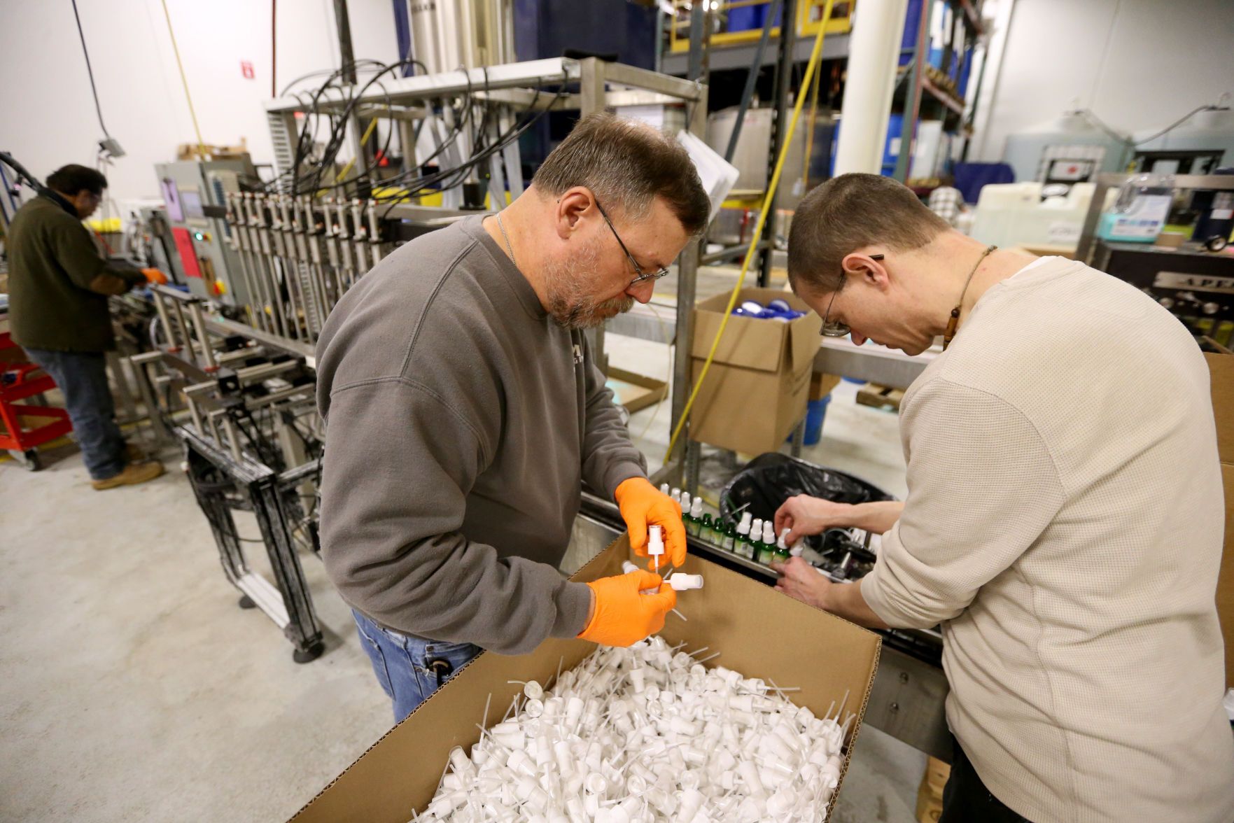 Gene Fangman (left) and Jeremy Crubaugh put caps on bottles at Higley Industries in Dyersville, Iowa, on Monday, Feb. 14, 2022.    PHOTO CREDIT: JESSICA REILLY