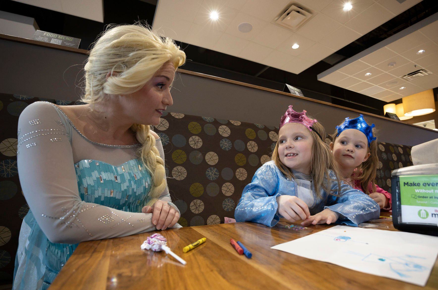 Traci Yeo, as Elsa, and owner of Royal T Princesses and Superheroes, greets Skylar, 7, (center) and Charlie Kearney, 4, at Wahlburgers in Hy-Vee on South Locust Street in Dubuque on Friday.    PHOTO CREDIT: Stephen Gassman
