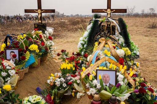 Flowers are placed around the graves of Ukrainian military servicemen Roman Rak and Mykola Mykytiuk in Starychi, western Ukraine, Wednesday, March 16, 2022. Rak and Mykytiu were killed during Sunday