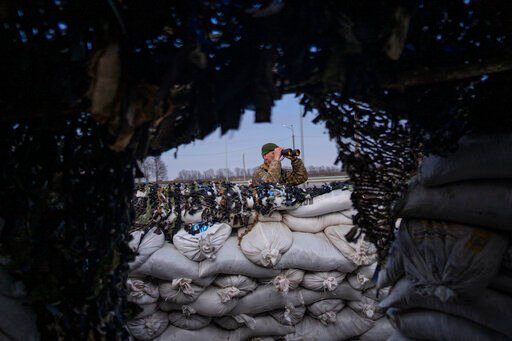 A Ukrainian soldier looks through binoculars at a military check point, in Lityn, Ukraine, Wednesday, March 16, 2022. (AP Photo/Rodrigo Abd)    PHOTO CREDIT: Rodrigo Abd