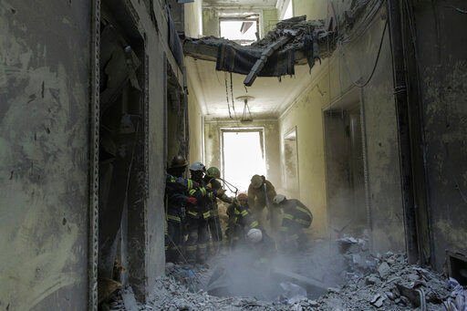 Ukrainian Emergency Service workers take a body out of debris at the City Hall building in the central square following the Russian shelling in Kharkiv, Ukraine, Wednesday, March 16, 2022. (AP Photo/Pavel Dorogoy)    PHOTO CREDIT: Pavel Dorogoy