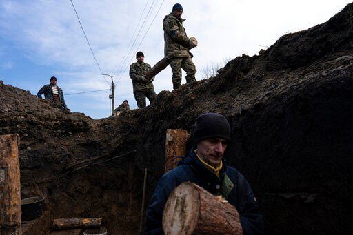 Soldiers carry wooden logs while building a trench, in Lityn, Ukraine, Wednesday, March 16, 2022. (AP Photo/Rodrigo Abd)    PHOTO CREDIT: Rodrigo Abd