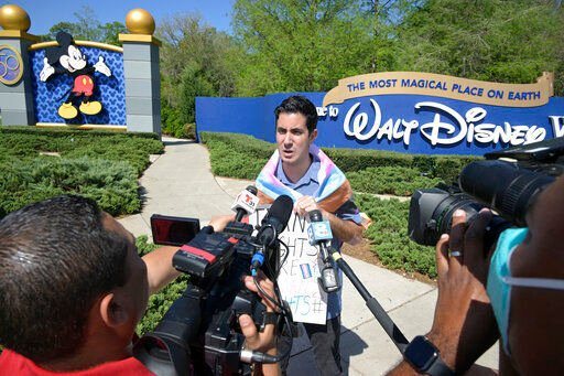 Disney cast member Nicholas Maldonado talks to reporters while protesting his company
