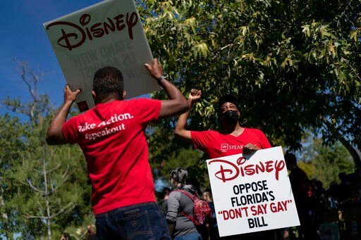 Two LGBTQ supporters hold signs to protest Disney