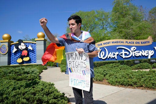 Disney cast member Nicholas Maldonado acknowledges a passing motorist honking support, while protesting his company