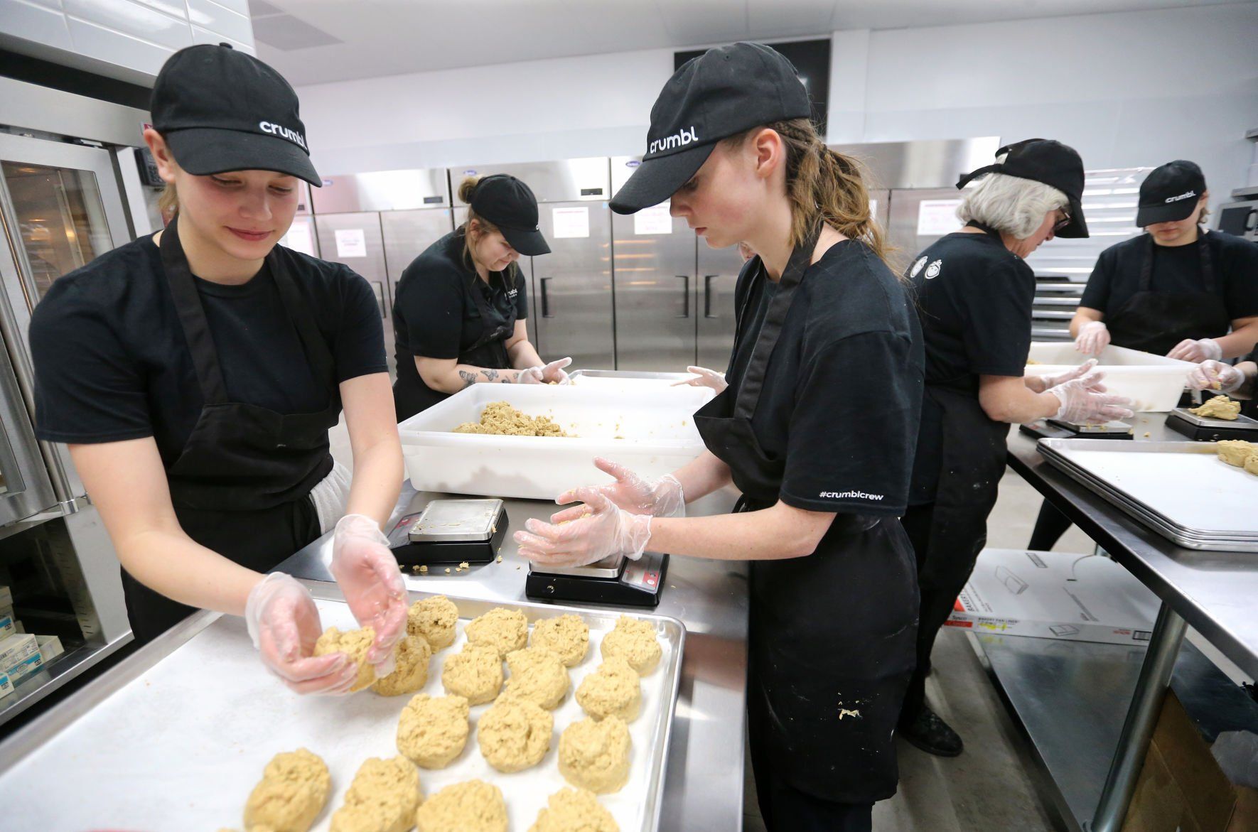 Cailyn Lord (from left), Hayley Francois and Keilah Small form balls of oatmeal cookies at Crumbl Cookies in Dubuque on Wednesday, March 23, 2022. The store opens Friday, March 25.    PHOTO CREDIT: JESSICA REILLY