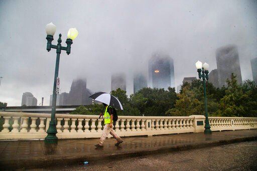 FILE - A pedestrian walks on the Sabine Street Bridge on the foreground of the Houston skyline during the Tropical Storm Beta Tuesday, Sept. 22, 2020, in Houston. (Marie D. De Jesús/Houston Chronicle via AP)    PHOTO CREDIT: Marie D. De Jesús