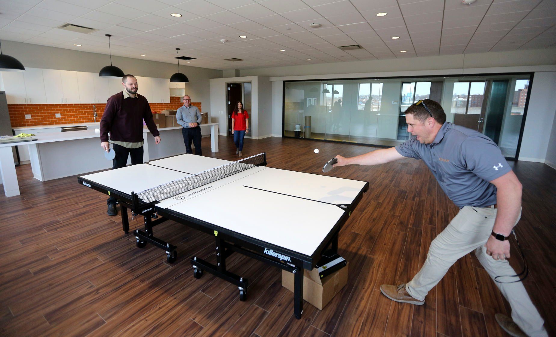 Conlon Construction employees Brandon Nanke (left) plays ping pong in the employee lounge with Ryan Koopmann as Keefe Gaherty and Libby Redfearn observe. The company is moving into the building at 501 Bell St. in Dubuque.    PHOTO CREDIT: Dave Kettering