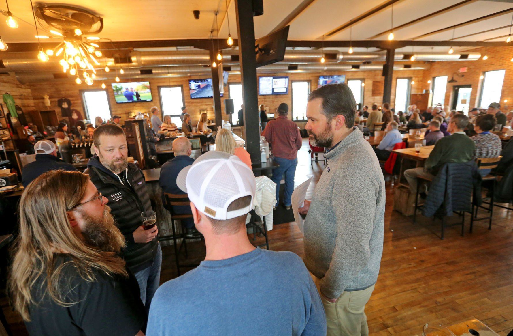 Nick Ashton (from left), of Cascade, Iowa; Daryl Hoedtke, of Chicago; Eric Miller, of Cascade, Iowa; and Mike Siegel, of Chicago, talk during a Farm to Brew event at Textile Brewing Co. in Dyersville, Iowa, on Wednesday, March 30, 2022.    PHOTO CREDIT: JESSICA REILLY