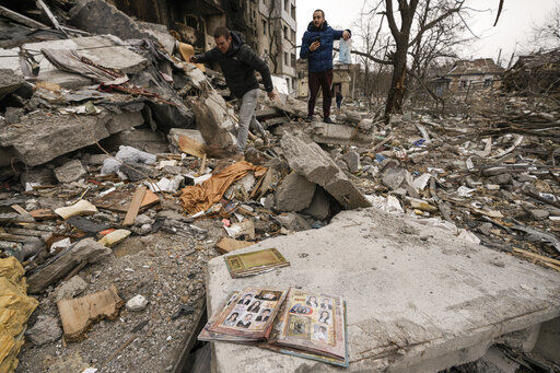 People look for personal belongings in the rubble of an apartment building destroyed during fighting between Ukrainian and Russian forces in Borodyanka, Ukraine, Tuesday, April 5, 2022. Ukrainian President Volodymyr Zelenskyy accused Russian troops of gruesome atrocities in Ukraine and told the U.N. Security Council on Tuesday that those responsible should immediately be brought up on war crimes charges in front of a tribunal like the one set up at Nuremberg after World War II. (AP Photo/Vadim Ghirda)    PHOTO CREDIT: Vadim Ghirda