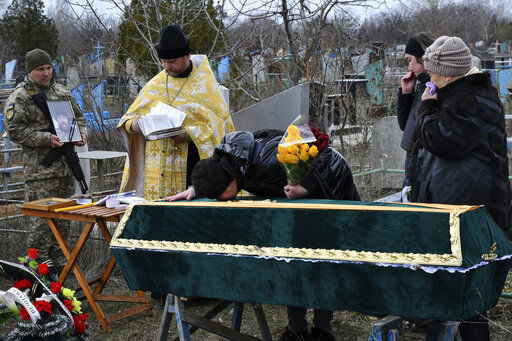 Relatives and friends stands by the coffin of Ukrainian serviceman Anatoly German during a funeral ceremony in Kramatorsk, Ukraine, Tuesday, April 5, 2022. Anatoly German was killed during fightings between Russian and Ukrainian forces near the city of Severodonetsk. He leaves a wife, daughter Adelina, 9, son Kirill, 3. (AP Photo/Andriy Andriyenko)    PHOTO CREDIT: Andriy Andriyenko
