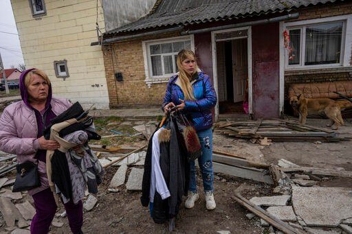 Relatives of three men killed in the courtyard of a house, remove clothing and valuables from the home in Bucha, in the outskirts of Kyiv, Ukraine, Tuesday, April 5, 2022. (AP Photo/Rodrigo Abd)    PHOTO CREDIT: Rodrigo Abd