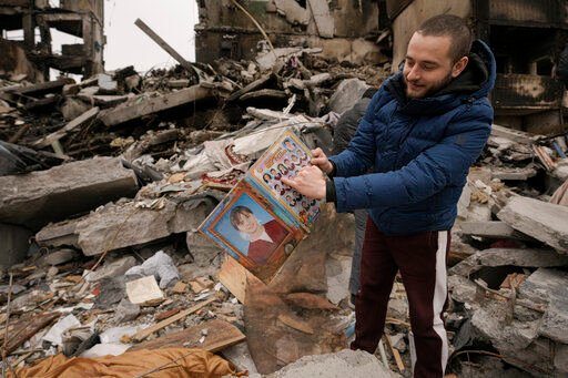 Dmitriy Evtushkov, 25, points to his picture in a primary school album retrieved from the rubble of an apartment building destroyed during fighting between Ukrainian and Russian forces in Borodyanka, Ukraine, Tuesday, April 5, 2022. Ukrainian President Volodymyr Zelenskyy accused Russian troops of gruesome atrocities in Ukraine and told the U.N. Security Council on Tuesday that those responsible should immediately be brought up on war crimes charges in front of a tribunal like the one set up at Nuremberg after World War II. (AP Photo/Vadim Ghirda)    PHOTO CREDIT: Vadim Ghirda