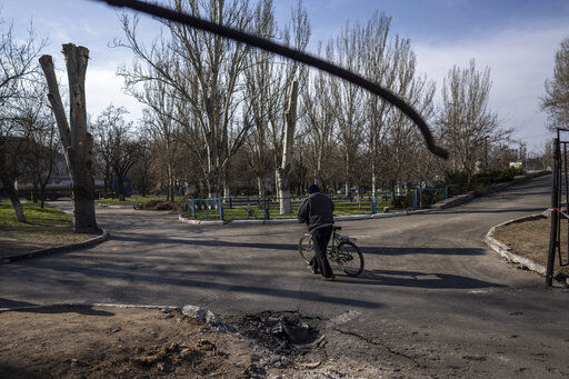 A man makes his way with his bicycle behind the place of a rocket hit the ground, two days ago outside a hospital, in Mykolaiv Ukraine, Tuesday, April 5, 2022.(AP Photo/Petros Giannakouris)    PHOTO CREDIT: Petros Giannakouris