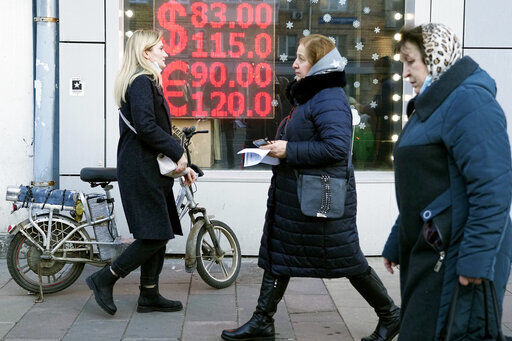 FILE - People walk past a currency exchange office screen displaying the exchange rates of U.S. Dollar and Euro to Russian Rubles in Moscow, on Feb. 28, 2022. The U.S. Treasury Department will not allow any dollar debt payments to be made from Russian government accounts at U.S. financial institutions, an agency spokesperson said Tuesday morning. (AP Photo/Pavel Golovkin, File)    PHOTO CREDIT: Pavel Golovkin