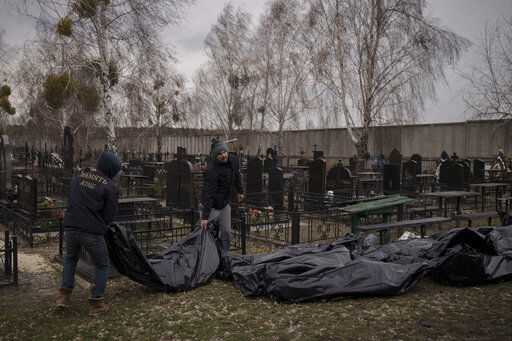 Workers carry the body of people found dead to a cemetery in Bucha, outskirts of Kyiv, Ukraine, Tuesday, April 5, 2022. Ukraine’s president told the U.N. Security Council on Tuesday that the Russian military must be brought to justice immediately for war crimes, accusing invading troops of the worst atrocities since World War II. He stressed that Bucha was only one place and there are more with similar horrors. (AP Photo/Felipe Dana)    PHOTO CREDIT: Felipe Dana