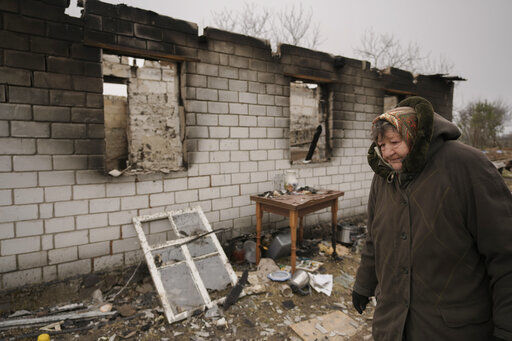 A woman walks by a house destroyed while her village was occupied by Russian troops in Andriivka, Ukraine, Tuesday, April 5, 2022. Ukrainian President Volodymyr Zelenskyy accused Russian troops of gruesome atrocities in Ukraine and told the U.N. Security Council on Tuesday that those responsible should immediately be brought up on war crimes charges in front of a tribunal like the one set up at Nuremberg after World War II.(AP Photo/Vadim Ghirda)    PHOTO CREDIT: Vadim Ghirda