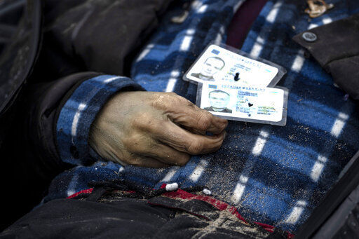 Identification cards on a man as policemen work on the indentification process following the killing of civilians in Bucha, before sending the bodies to the morgue, on the outskirts of Kyiv, Ukraine, Wednesday, April 6, 2022. (AP Photo/Rodrigo Abd)    PHOTO CREDIT: Rodrigo Abd