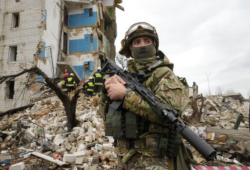A Ukrainian soldier stands against the background of an apartment house ruined in the Russian shelling in Borodyanka, Ukraine, Wednesday, Apr. 6, 2022. (AP Photo/Efrem Lukatsky)    PHOTO CREDIT: Efrem Lukatsky