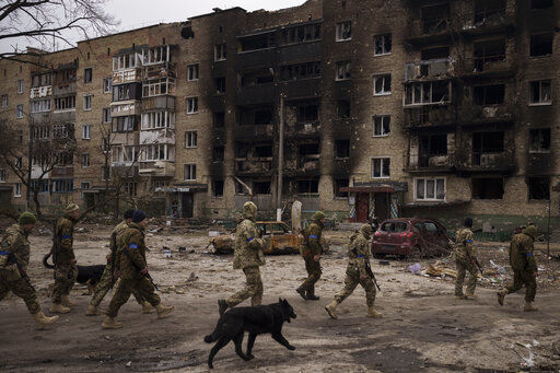 Ukrainian soldiers walk next to heavily damaged residential buildings in Irpin, on the outskirts of Kyiv, Ukraine, Wednesday, April 6, 2022. (AP Photo/Felipe Dana)    PHOTO CREDIT: Felipe Dana