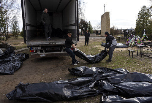 Cemetery workers load the corpses of civilians killed in Bucha, to be transported to the morgue, on the outskirts of Kyiv, Ukraine, Wednesday, April 6, 2022. (AP Photo/Rodrigo Abd)    PHOTO CREDIT: Rodrigo Abd