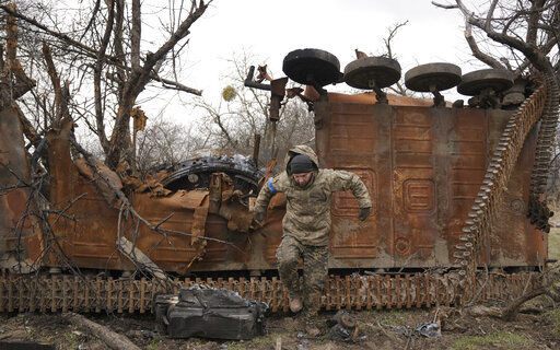 A Ukrainian serviceman jumps from a destroyed Russian fighting vehicle after collecting parts and ammunition in the village of Andriivka, Ukraine, heavily affected by fighting between Russian and Ukrainian forces, Wednesday, April 6, 2022. Several buildings in the village were reduced to mounds of bricks and corrugated metal and residents struggle without heat, electricity or cooking gas. (AP Photo/Vadim Ghirda)    PHOTO CREDIT: Vadim Ghirda
